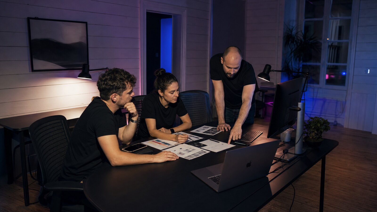 Equipe d'agence digitale en train de cadrer un projet dans un bureau premium de nuit